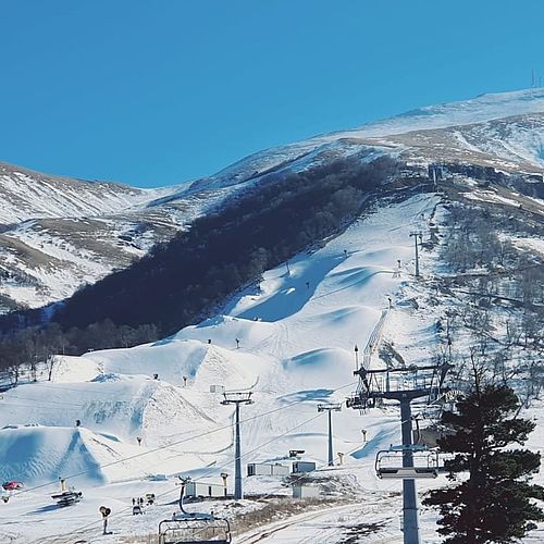 Panoramablick auf das Skigebiet Bakuriani in Georgien mit schneebedeckten Hängen, Skiliften und präparierten Pisten unter blauem Himmel