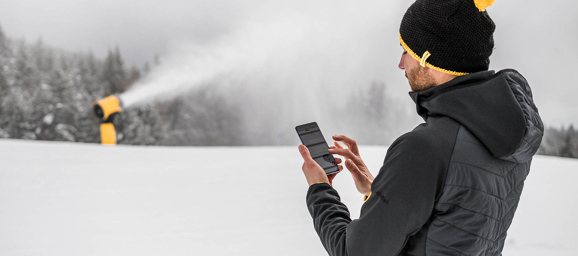 Mitarbeiter steuert TechnoAlpin Schneeerzeuger per Smartphone-App im Skigebiet