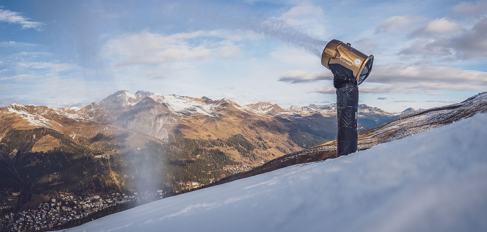 Panoramic view of gold TechnoAlpin TT10 No.1000 in operation on Davos ridge with Swiss alpine peaks