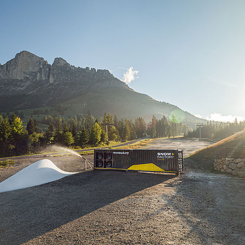 SnowFactory Polar Container produziert Schneehaufen bei Sonnenaufgang mit Dolomiten im Hintergrund