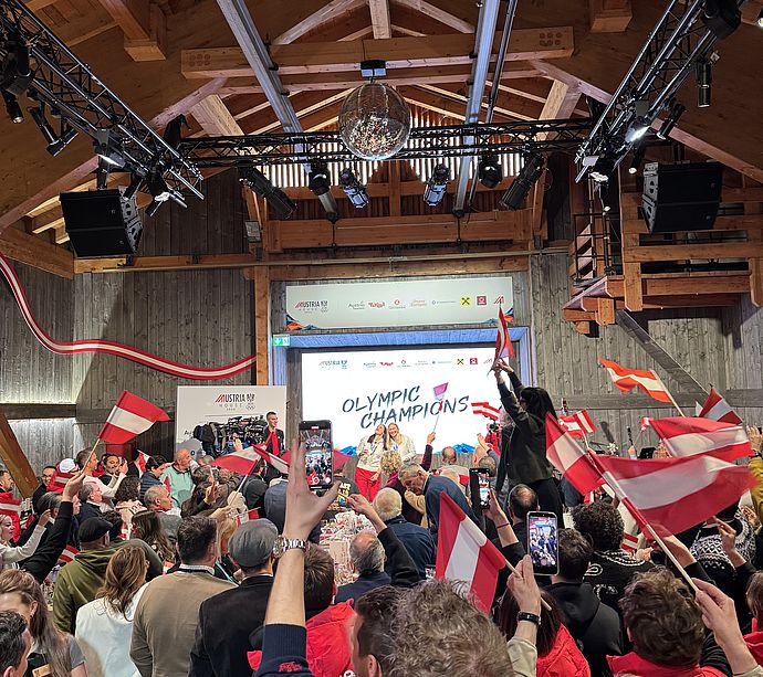 Cheering crowd with Austrian flags at Austria House celebrates Olympic champions on stage