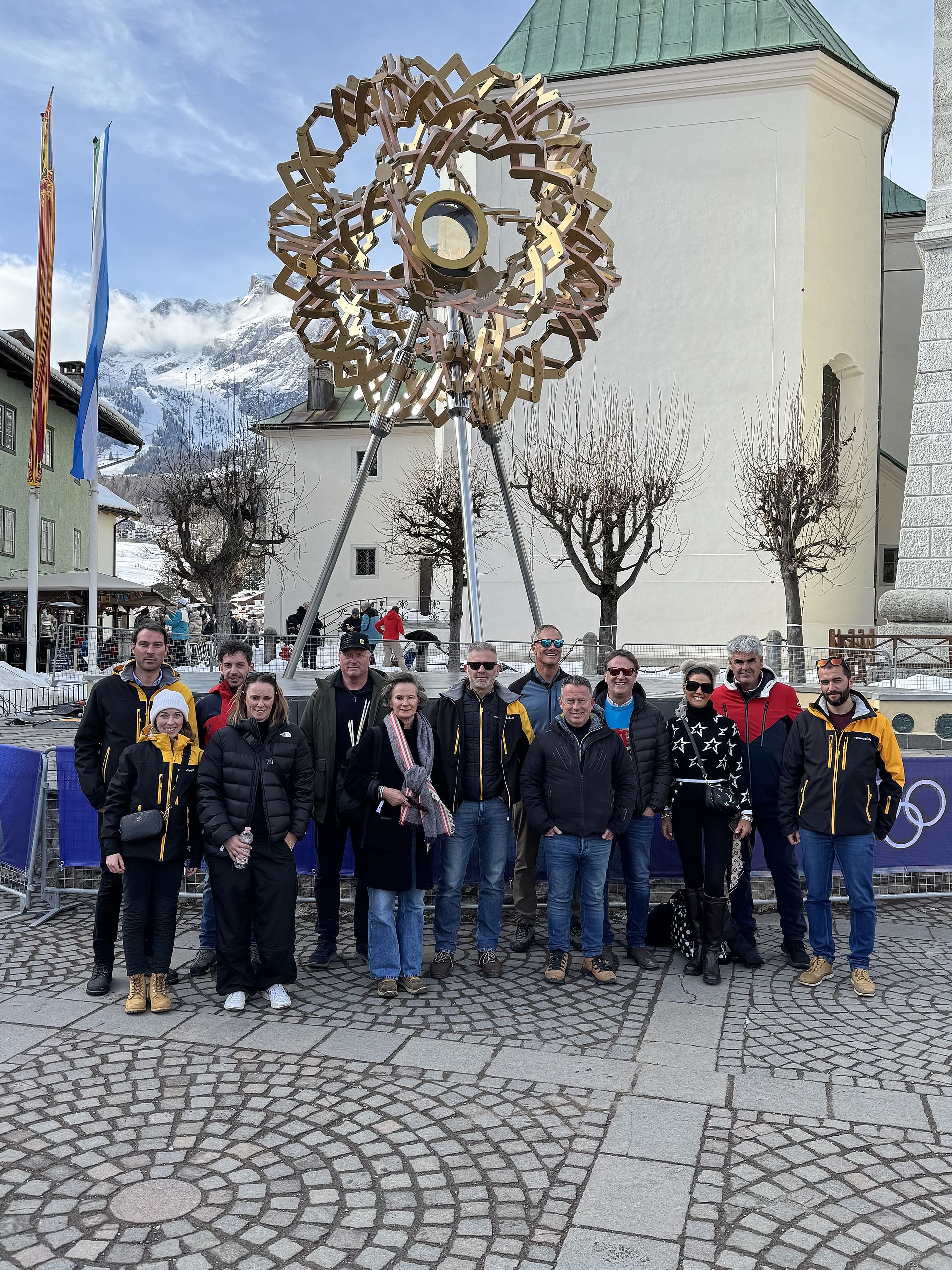 Group photo in front of golden snowflake sculpture in church square in Cortina at Olympics