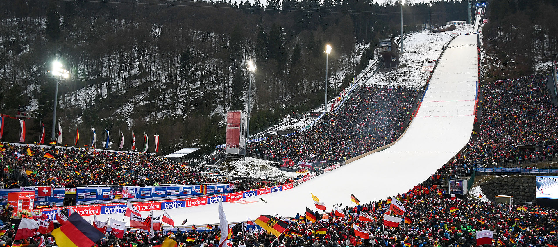 Skisprungschanze in Willingen bei Nacht mit voll besetzten Zuschauerrängen