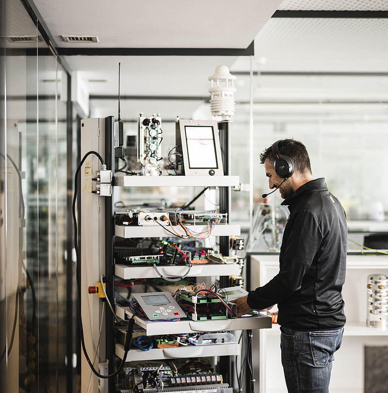 Technician with headset works on control technology and electronics in laboratory