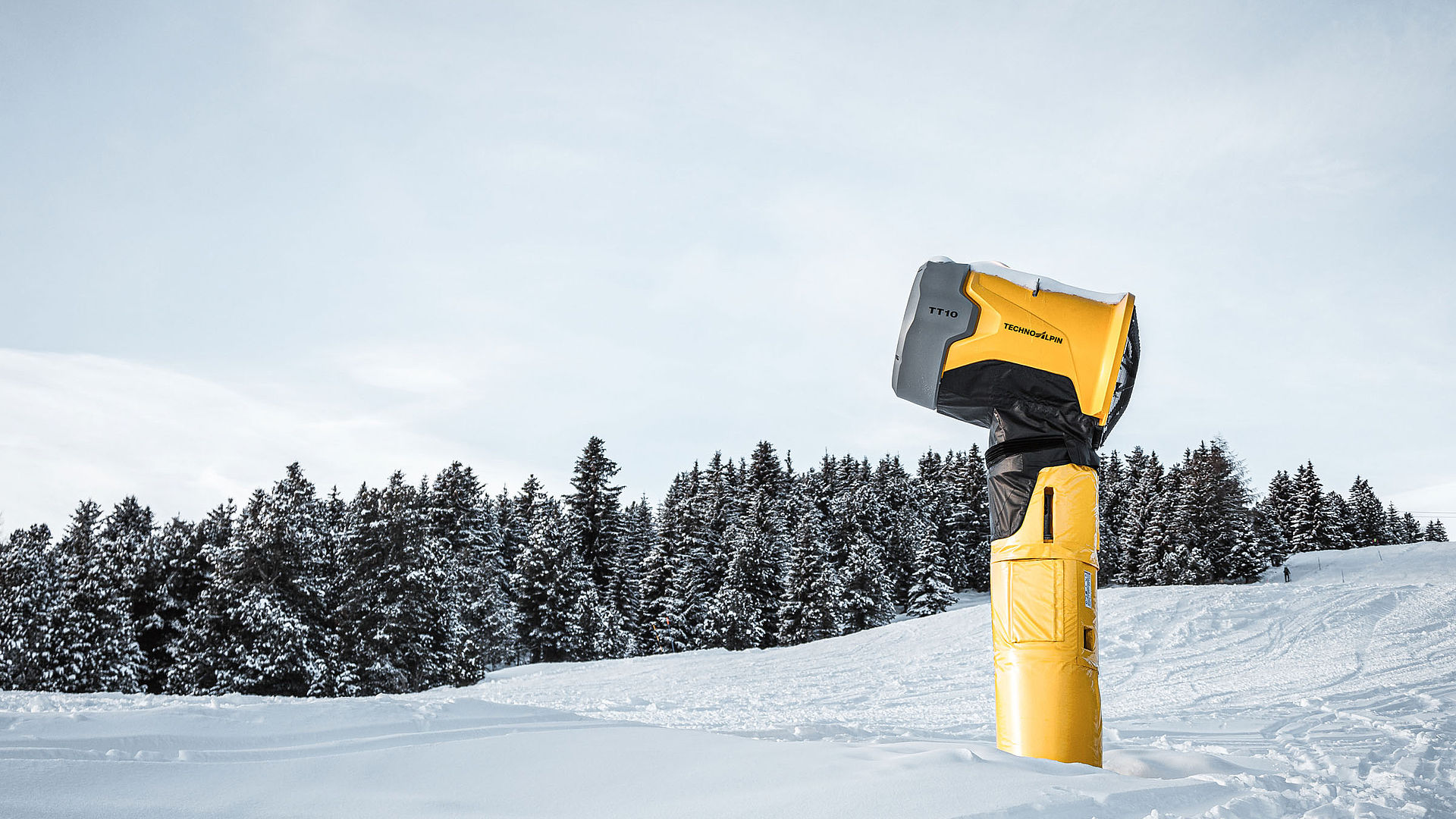TechnoAlpin TT10 Schneeerzeuger auf verschneiter Piste vor Nadelwald