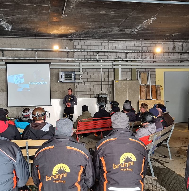 Sala formazione con partecipanti seduti in abbigliamento da sci davanti a schermo con presentazione finale.