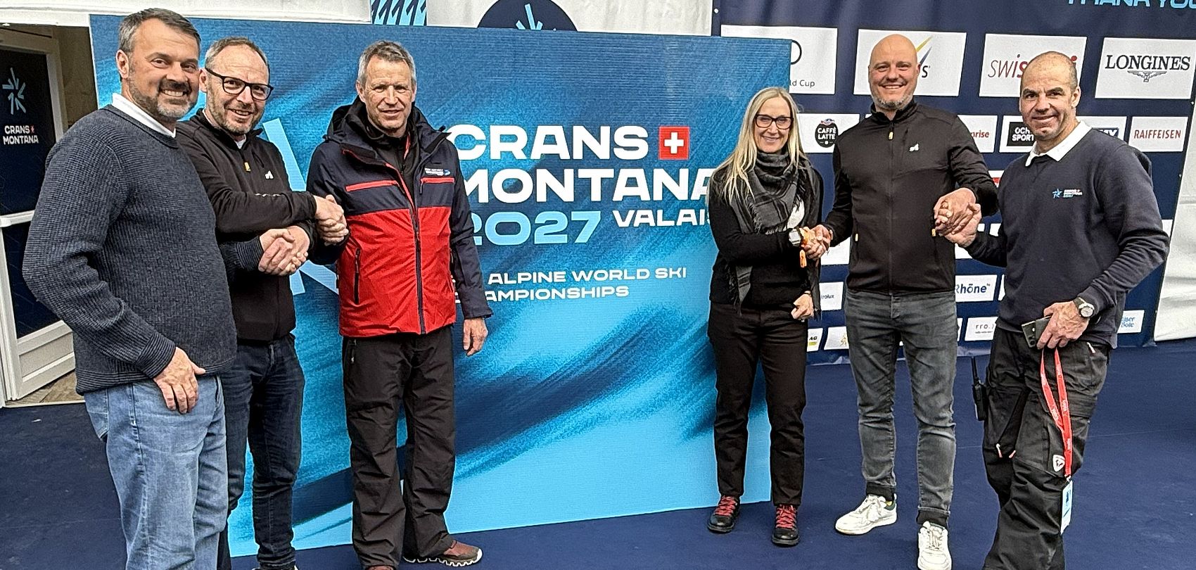 Handshake between TechnoAlpin and Crans Montana 2027 in front of FIS Alpine Ski World Championship banner