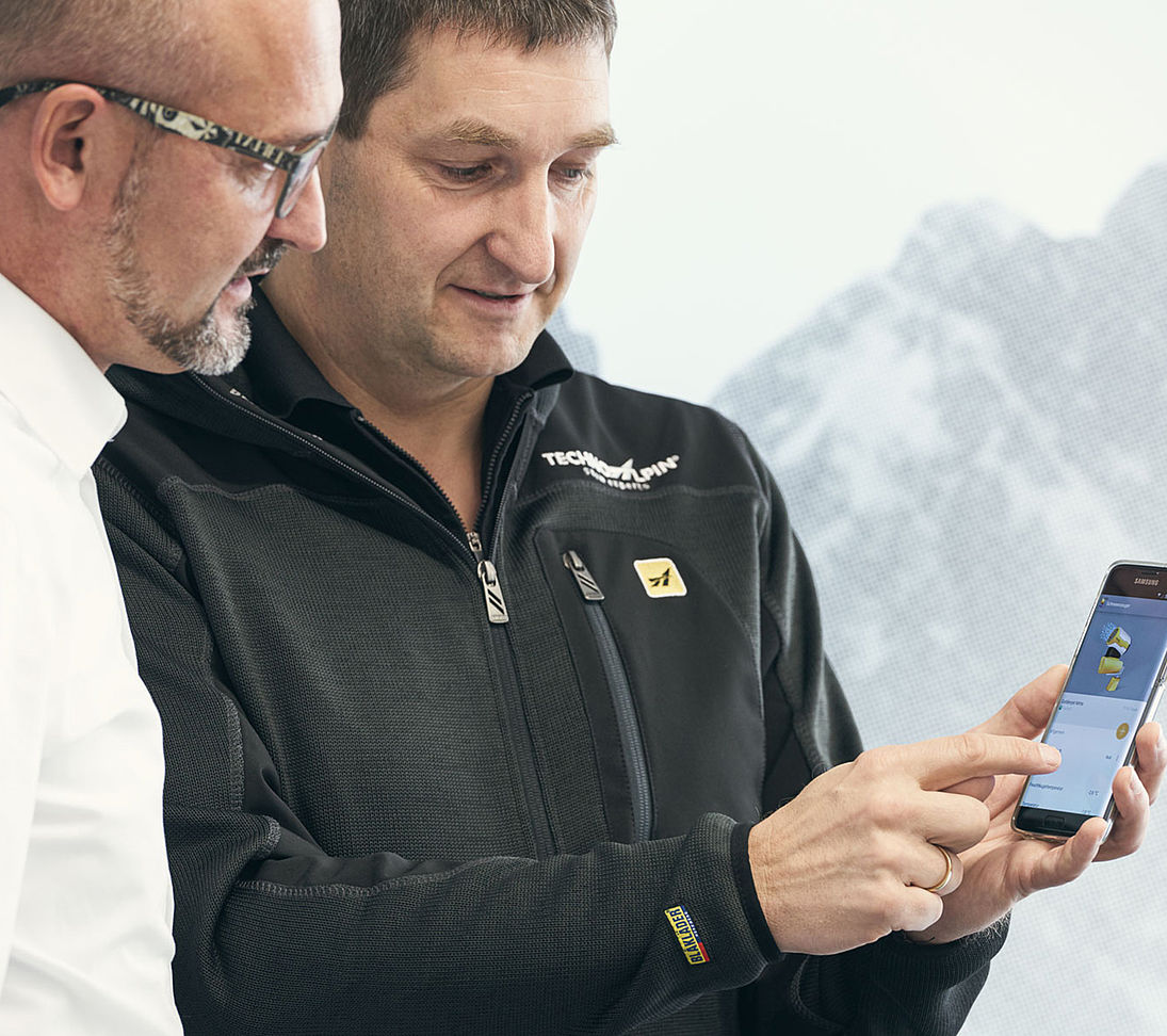TechnoAlpin Mitarbeiter zeigt Steuerungs-App für Beschneiungsanlage am Smartphone