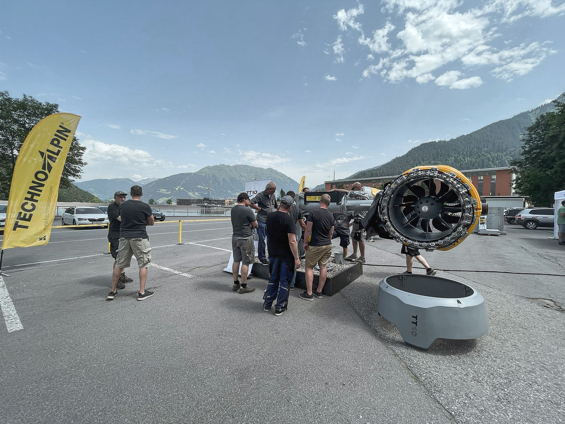 TechnoAlpin roadshow outdoors with TT10 snow generator and visitors in front of alpine panorama.