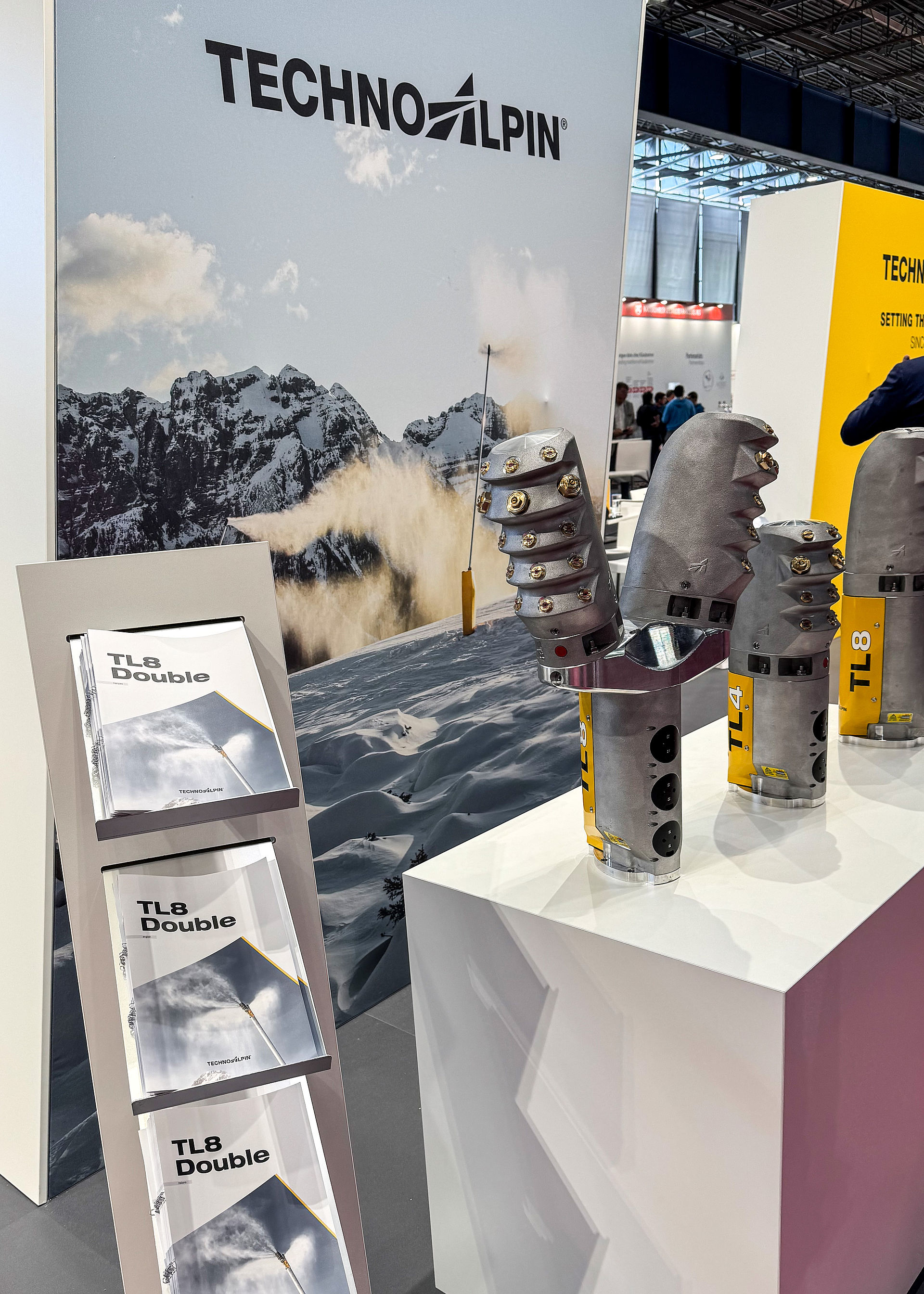 TechnoAlpin Messestand mit TL8 Double Broschüren und Schneeerzeuger-Düsenköpfen auf Podest