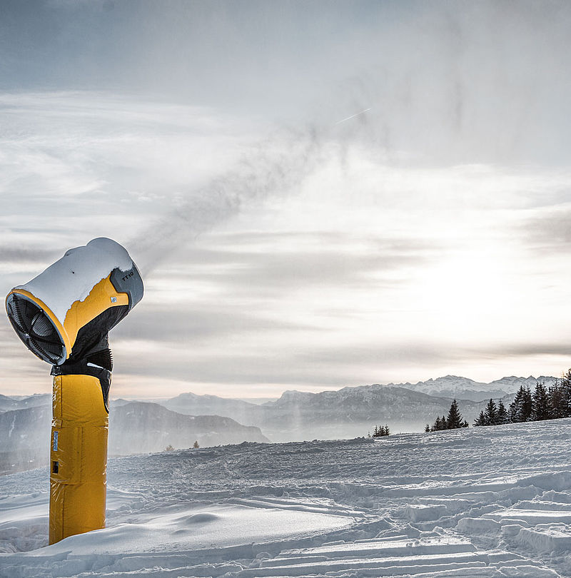 Enneigeur TechnoAlpin TT10 en action sur crête enneigée au coucher du soleil