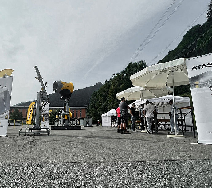 Overview of TechnoAlpin exhibition grounds with snow generators, beach flags and tents.