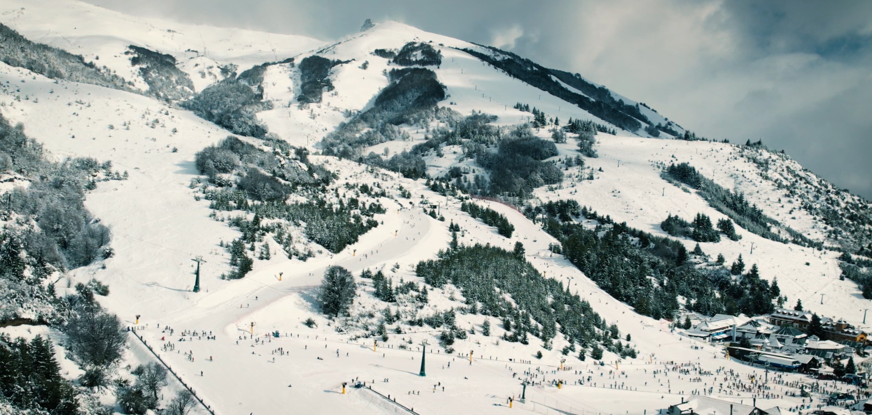 Aerial view of a snow-covered ski resort with slopes, lifts and valley station