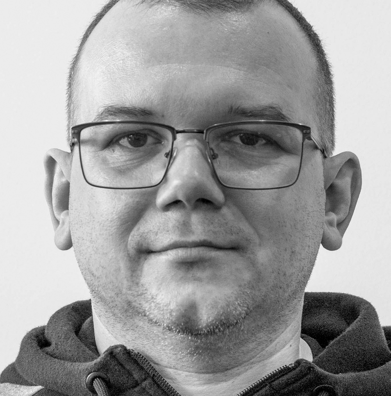 Schwarz-Weiß-Porträt eines Mannes mit Brille, Kurzhaarschnitt und Kapuzenjacke