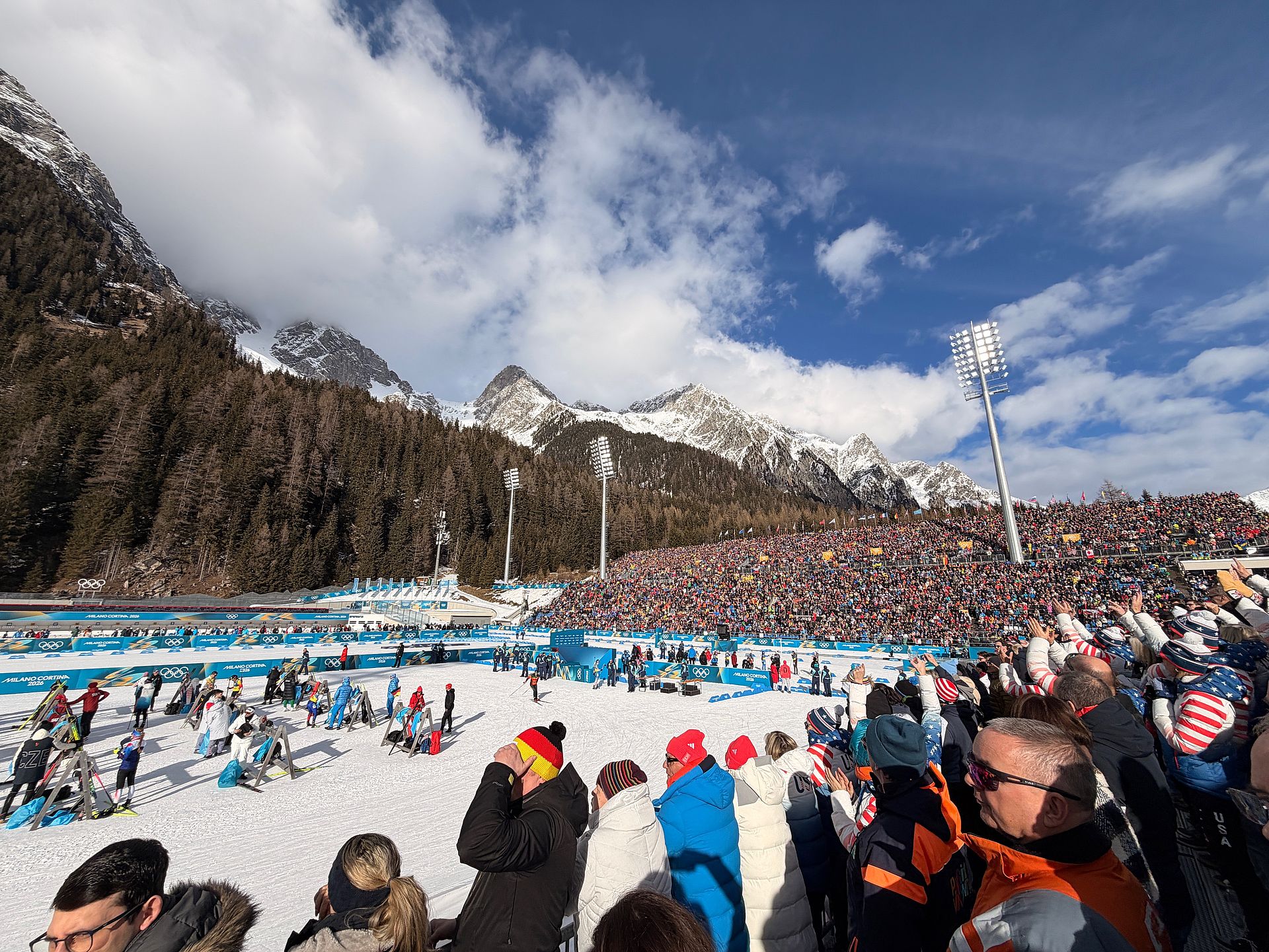 Olympic slope Tofane with spectators, Milano Cortina 2026 advertising banners and mountain fog