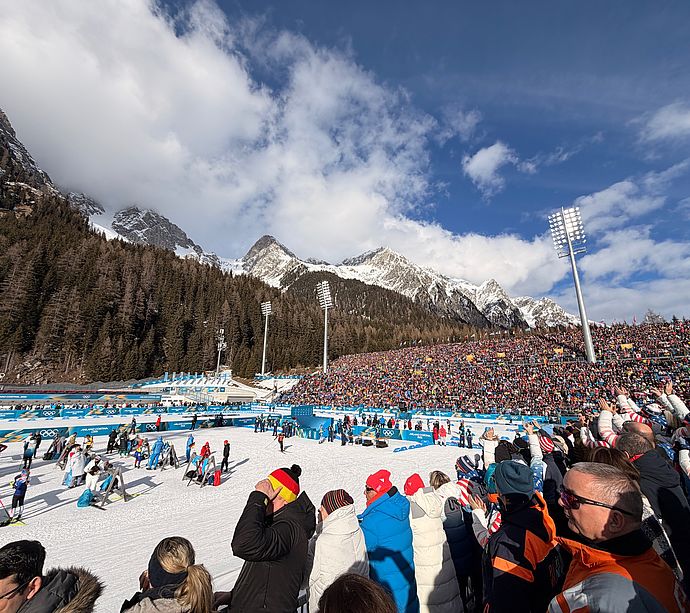 Olympic slope Tofane with spectators, Milano Cortina 2026 advertising banners and mountain fog