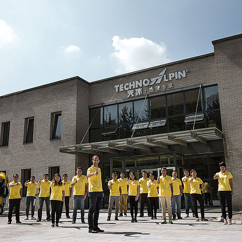 TechnoAlpin Team vor Niederlassung in China mit Firmenlogo am Gebäude