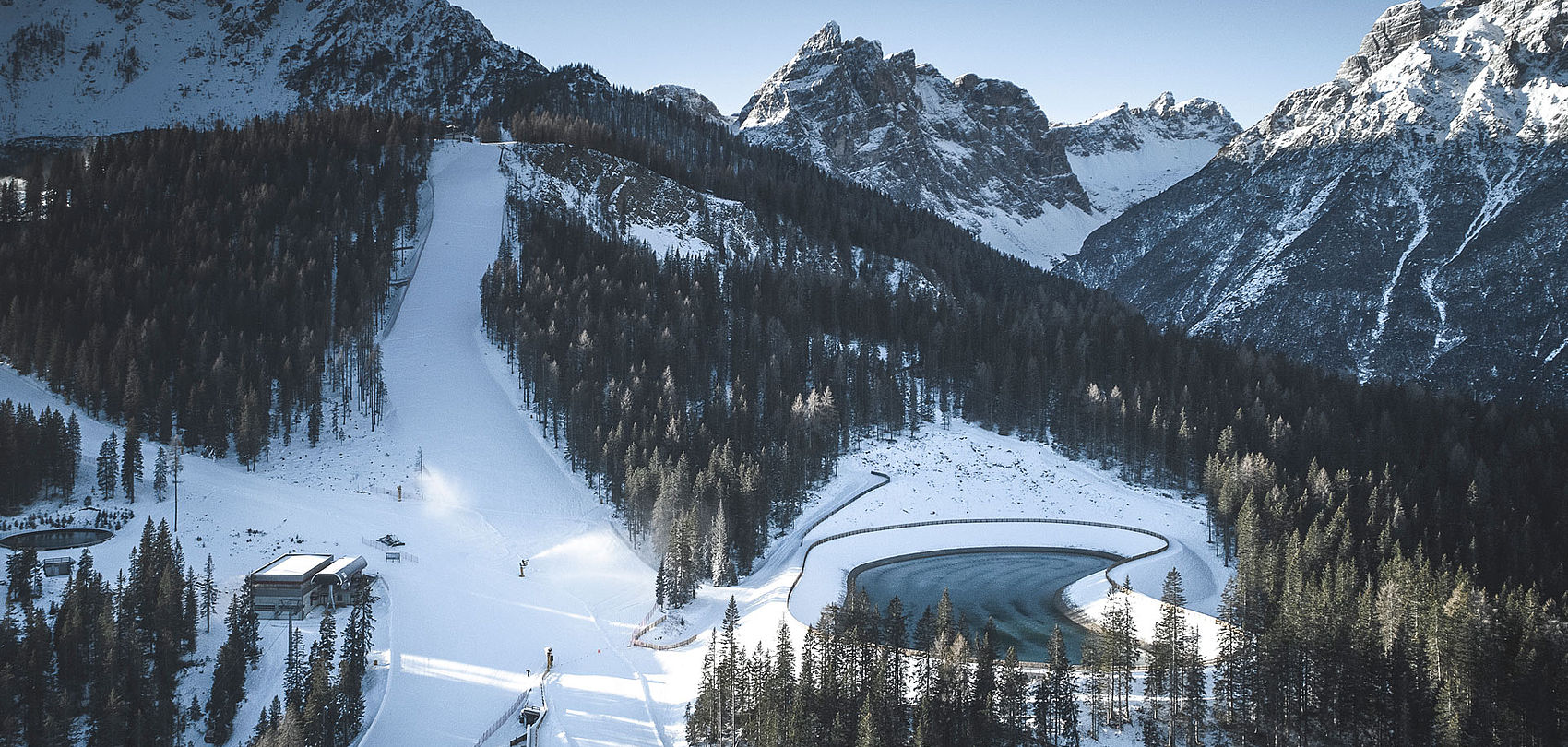 Vue aérienne de piste de ski avec lac de retenue au pied des Trois Cimes dans les Dolomites