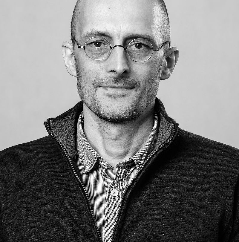 Jiri Krticka, TechnoAlpin Mitarbeiter, Schwarz-Weiß-Portrait mit Glatze, runder Brille und dezentralem Lächeln in dunklem Reißverschlusspullover