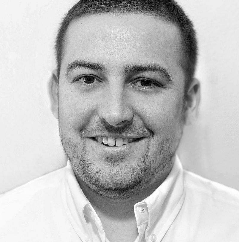 Peter Britz, TechnoAlpin Mitarbeiter, Portrait mit kurzem dunklem Haar, kurzem Bart und breitem herzlichem Lächeln in weißem Hemd