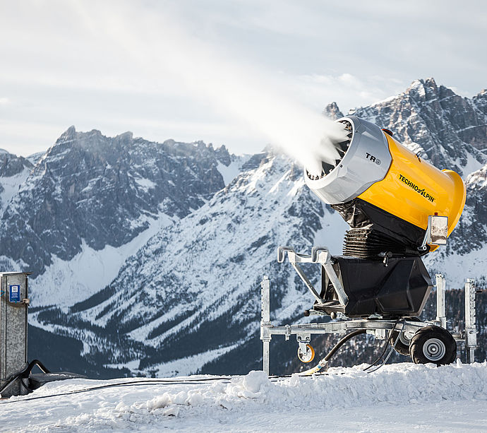 TR9 Schneekanone in Betrieb mit Schneestrahl vor verschneitem Dolomiten-Bergpanorama