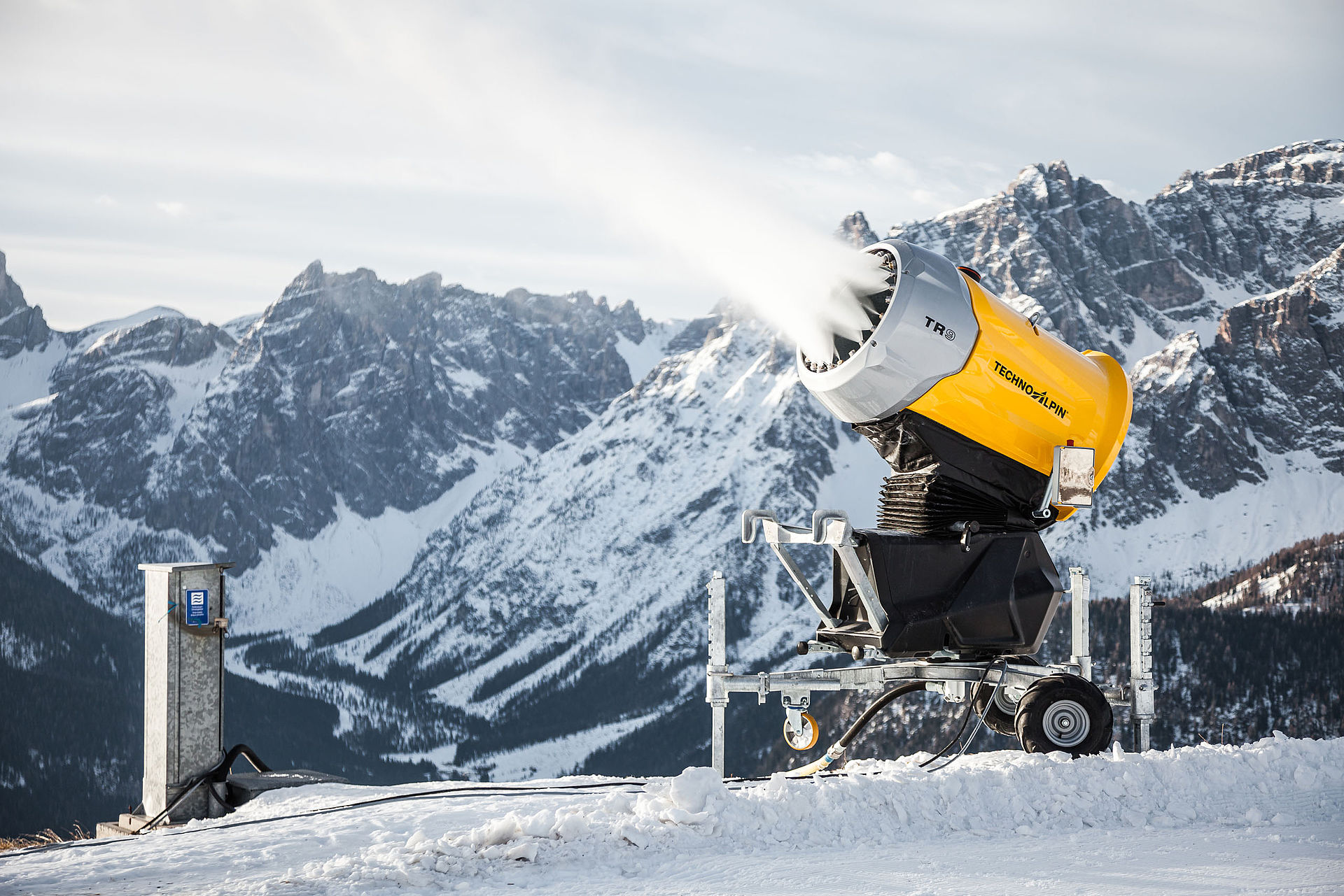 TR9 Schneekanone in Betrieb mit Schneestrahl vor verschneitem Dolomiten-Bergpanorama