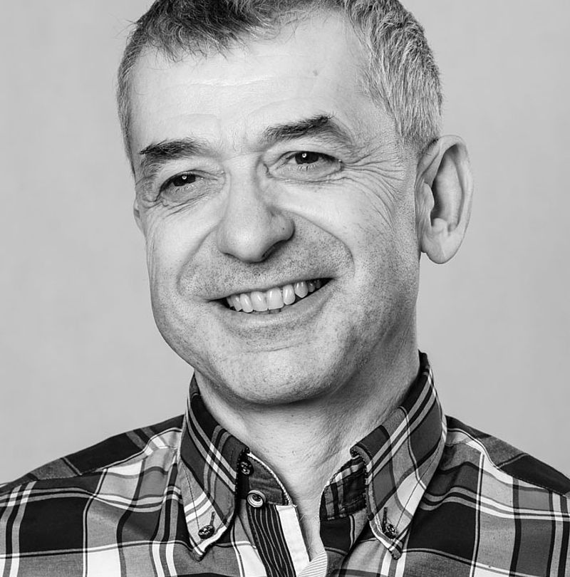 Lubomir Cintula, TechnoAlpin Mitarbeiter, Schwarz-Weiß-Portrait mit grauem Kurzhaar und herzlichem Lächeln in kariertem Hemd