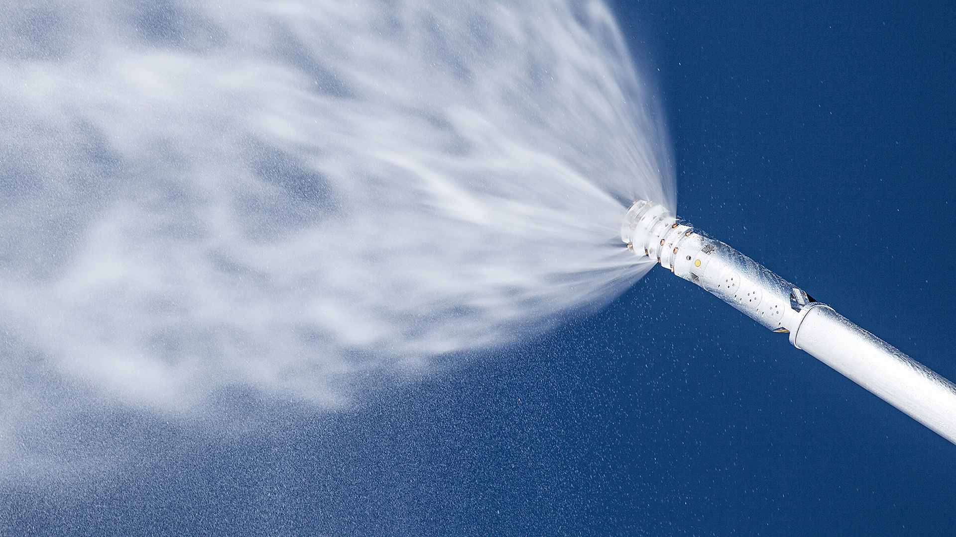 Schneekanone von TechnoAlpin versprüht feinen Schneestrahl vor tiefblauem Himmel