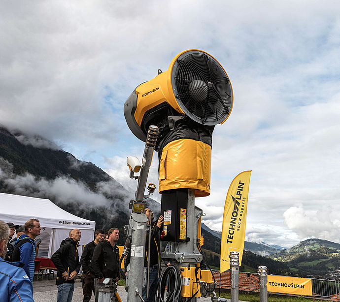 Innevatore a elica TechnoAlpin TT10 su palo alto con beach flag e visitatori al roadshow