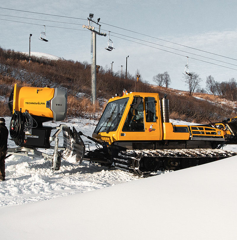 Yellow TechnoAlpin TR8 snow gun unit on snow groomer in snowy ski resort