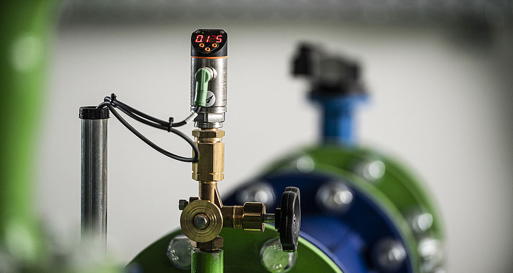 Pumpstation Innenansicht mit großer blauer Vertikalpumpe, grünen Rohrleitungen und Steuerungsmonitor