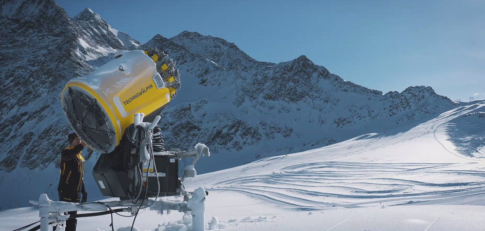 Gelber TechnoAlpin Propellerschneeerzeuger mit Techniker auf sonniger Bergpiste