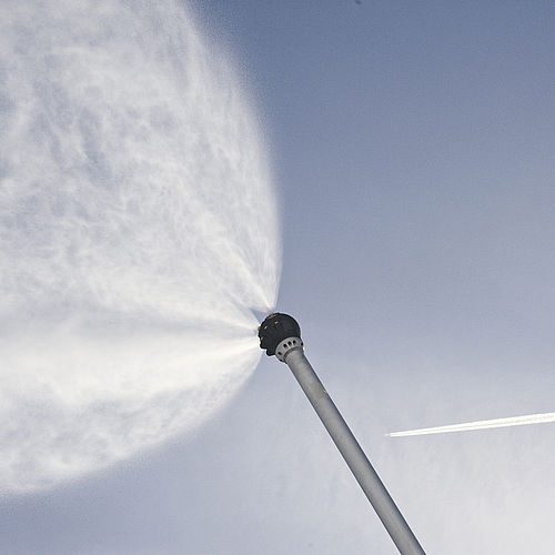 Reihe gelber TechnoAlpin Schneelanzen produzieren Schnee bei Sonnenuntergang vor dramatischen Alpengipfeln