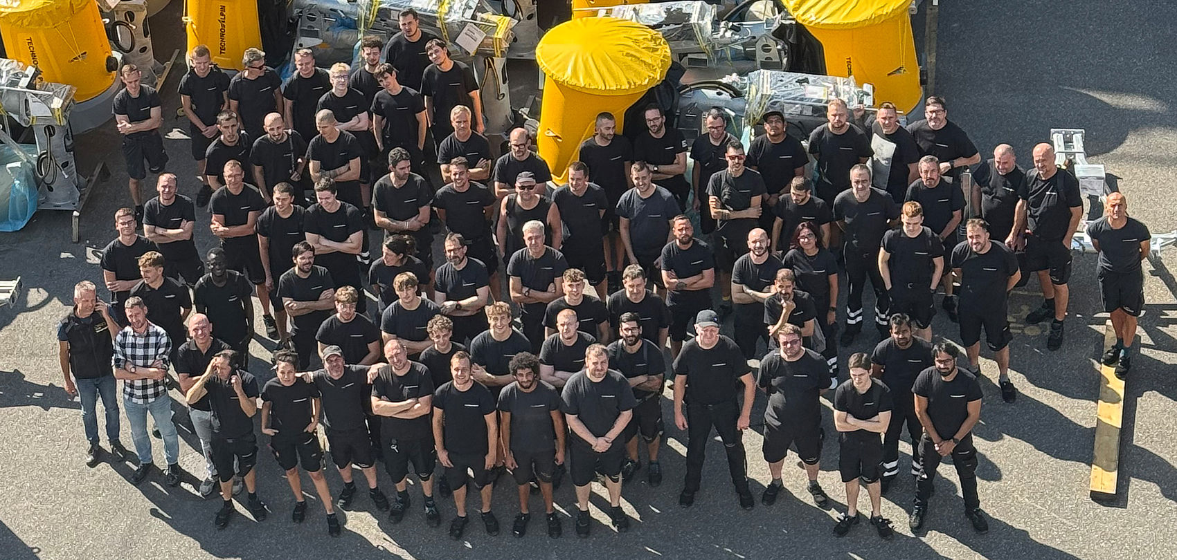 Gruppenfoto TechnoAlpin Mitarbeiter mit gelben Schneeerzeugern von oben
