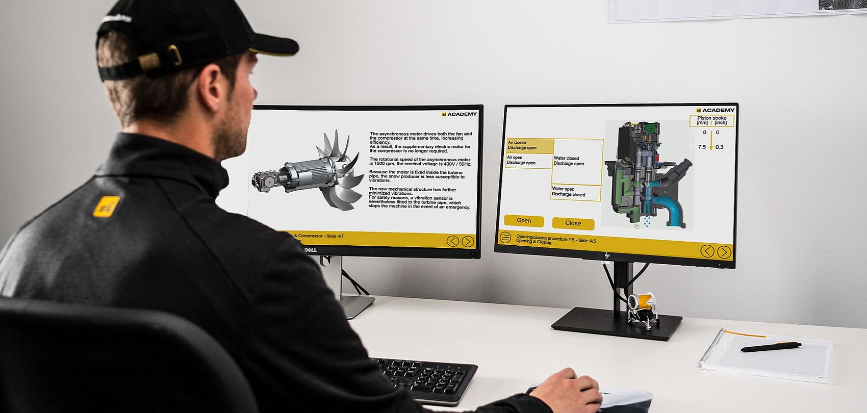 Man with cap at workstation with two monitors showing technical training content on motor and compressor
