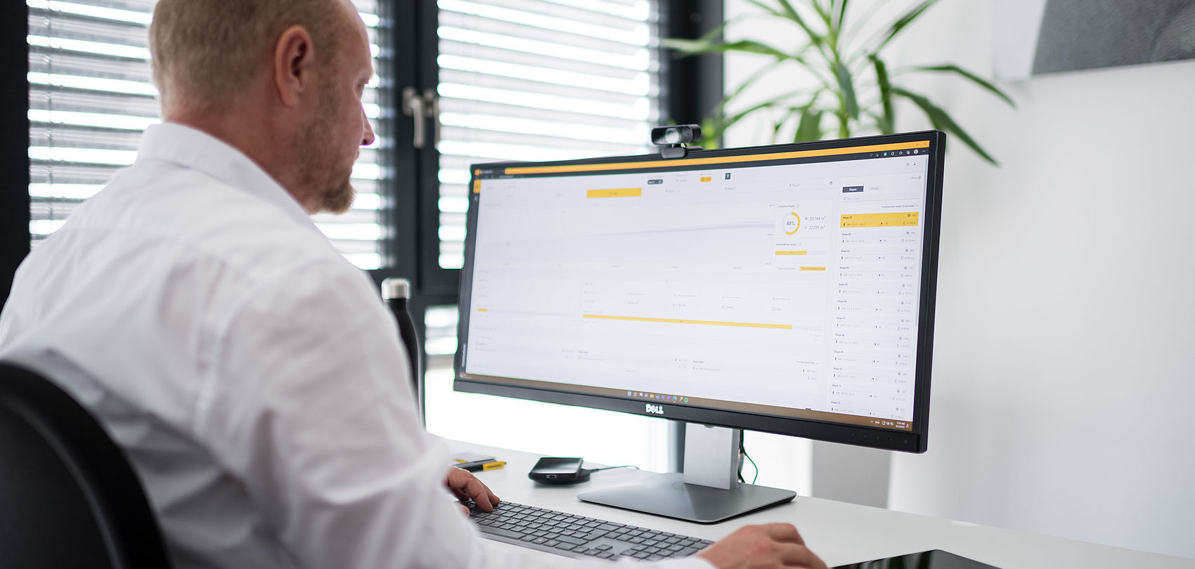 Homme au bureau visualisant le logiciel TechnoAlpin Snowmaster sur ecran incurve panoramique