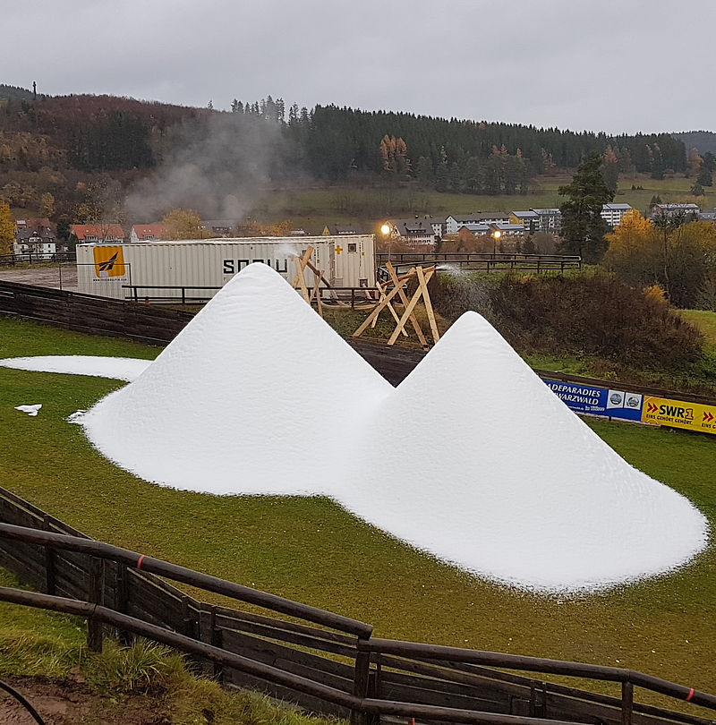 Schneehaufen aus der SNOW FACTORY auf grüner Wiese bei Plusgraden