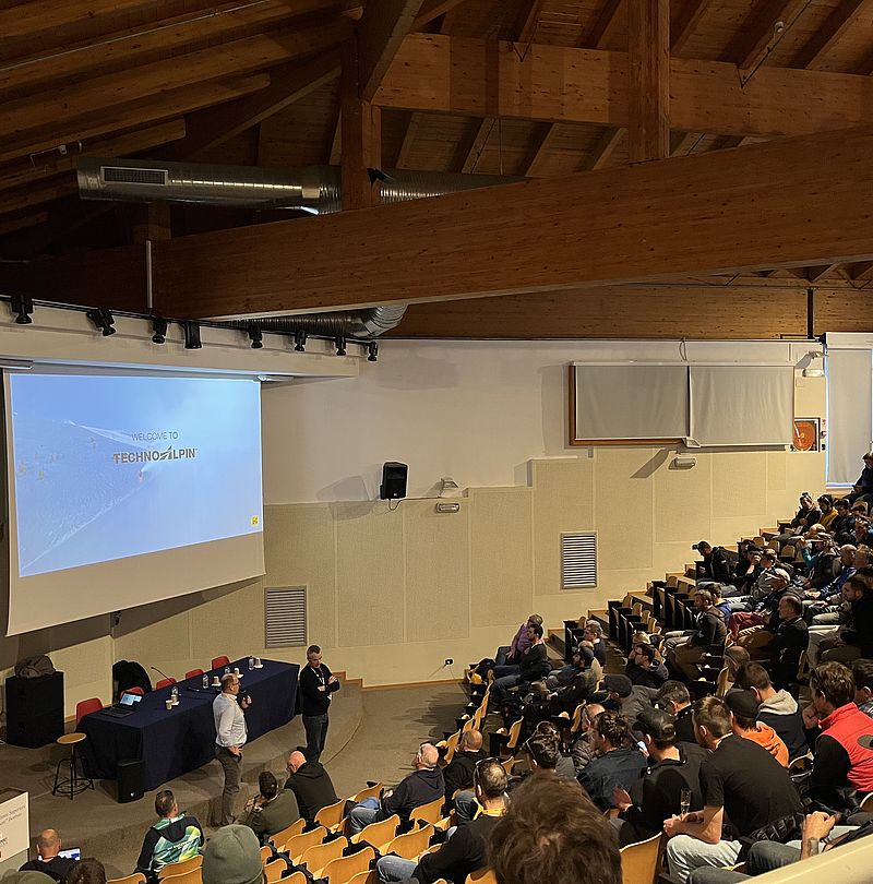 TechnoAlpin Präsentation in vollem Hörsaal mit Publikum und Vortragendem vor Leinwand