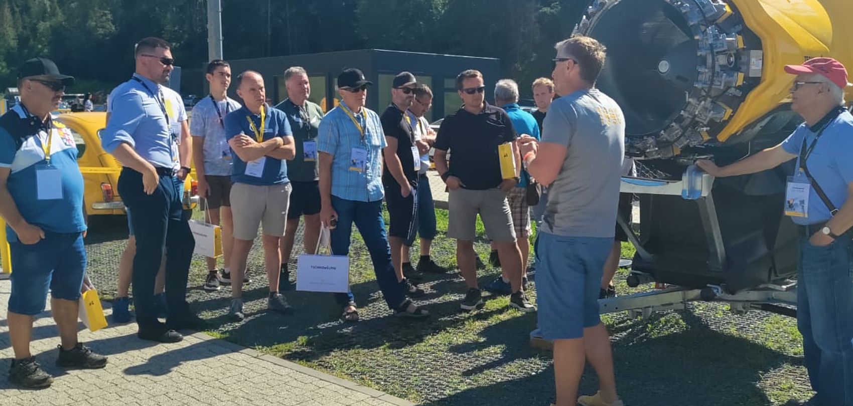 TechnoAlpin roadshow attendees in Slovakia listening to presenter demonstrating yellow snow gun outdoors