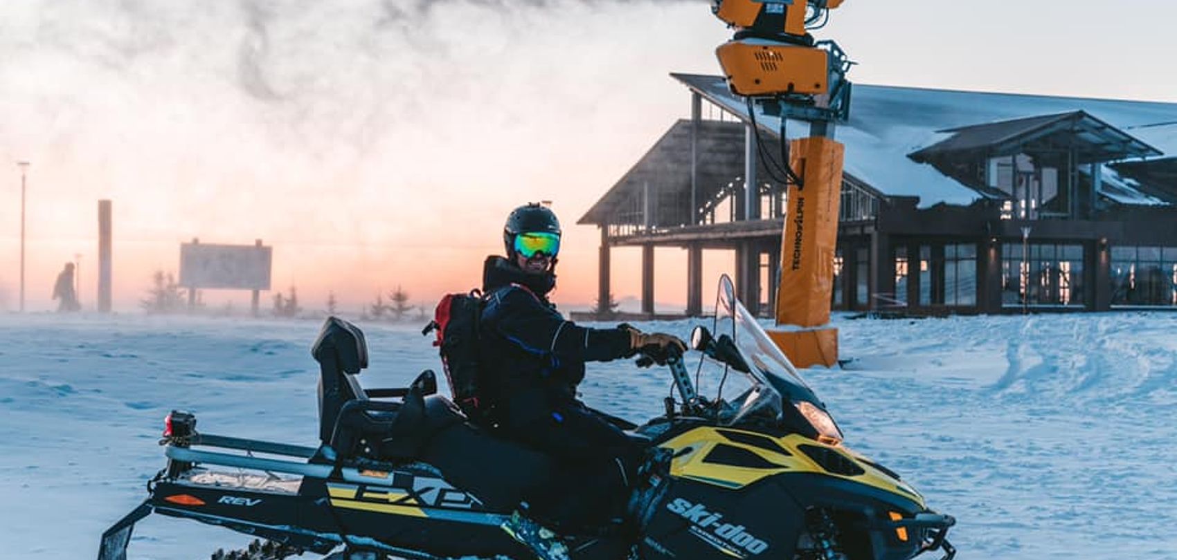 Person on snowmobile in front of TechnoAlpin snow cannon at Amirsoy ski resort