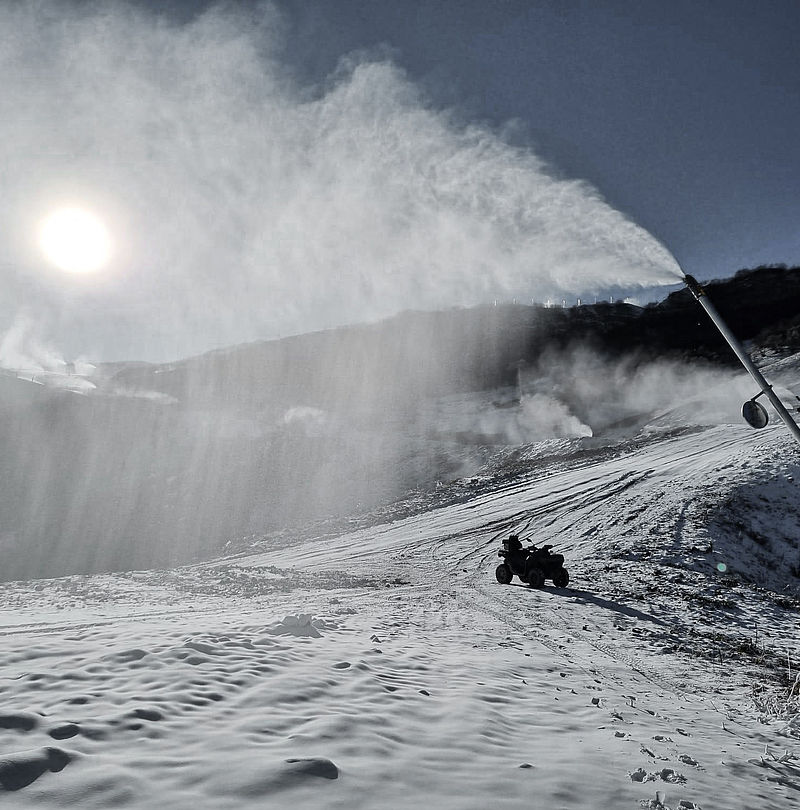 Schneelanze im Einsatz bei Sonnenaufgang, Quad auf Piste und Beschneiungsanlagen