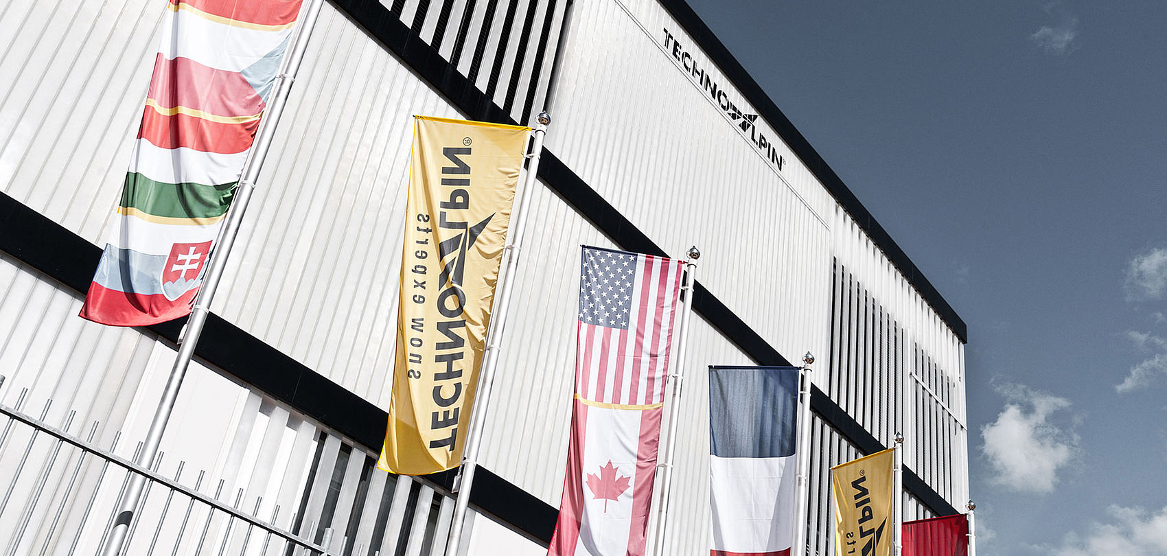 TechnoAlpin Hauptsitz mit internationalen Flaggen vor dem Gebäude