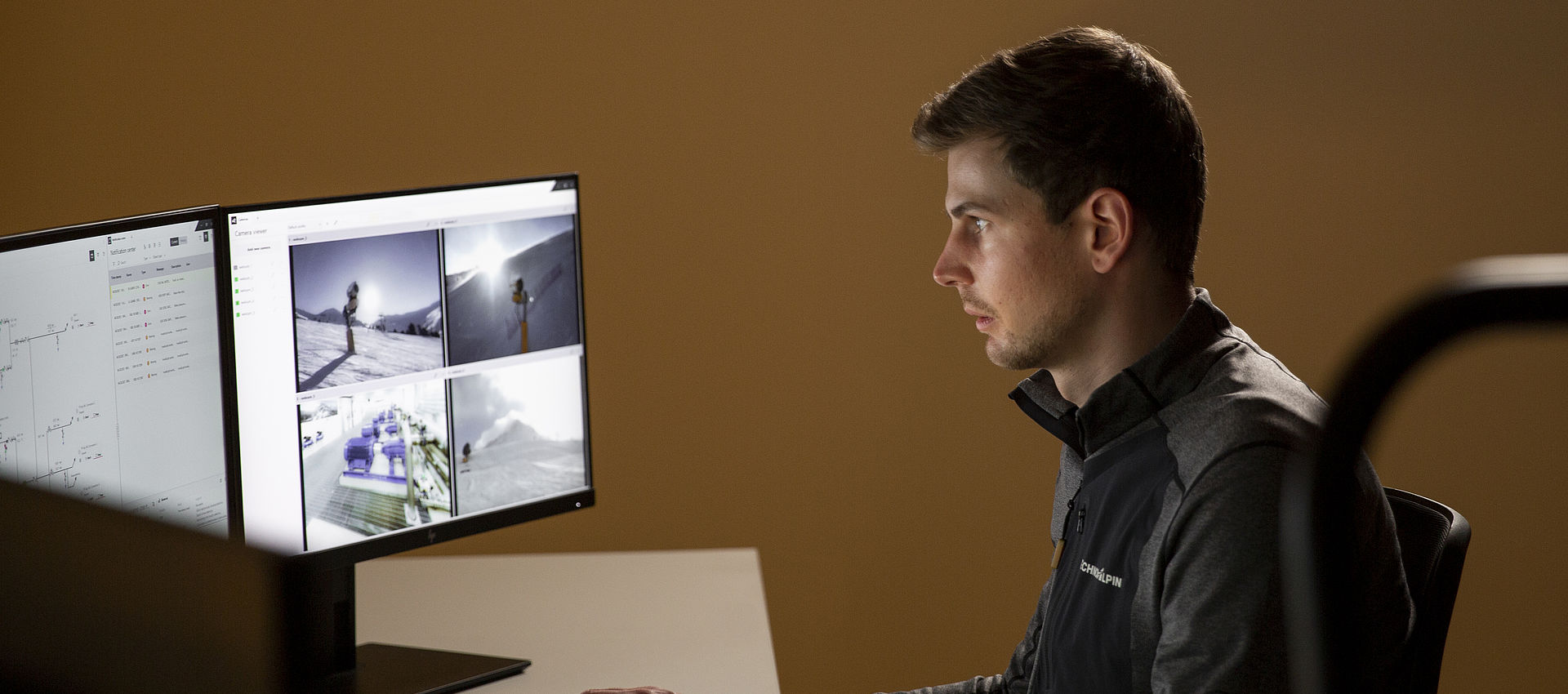 TechnoAlpin Mitarbeiter überwacht Beschneiungsanlage über Monitore mit Kameraansichten