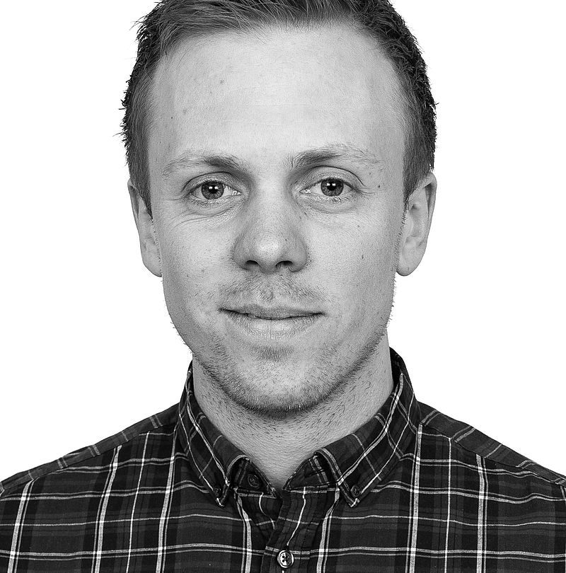 Erik Reinholdsson, TechnoAlpin Nordic Mitarbeiter, Schwarz-Weiß-Portrait mit kurzem blondem Haar, dezentralem Lächeln und dunklem Karohemd