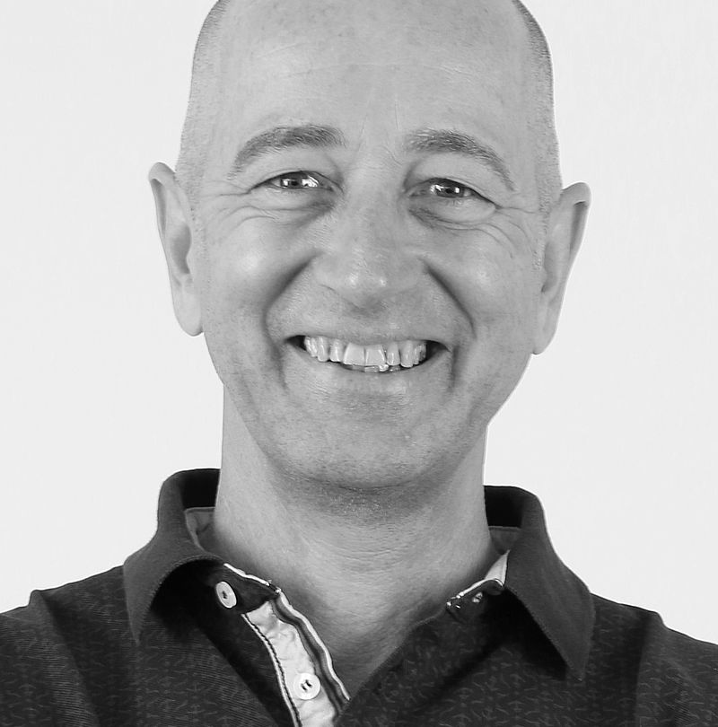 Robert Kramberger, TechnoAlpin Mitarbeiter, Schwarz-Weiß-Portrait mit breitem Lächeln, Glatze und dunklem Polo-Shirt