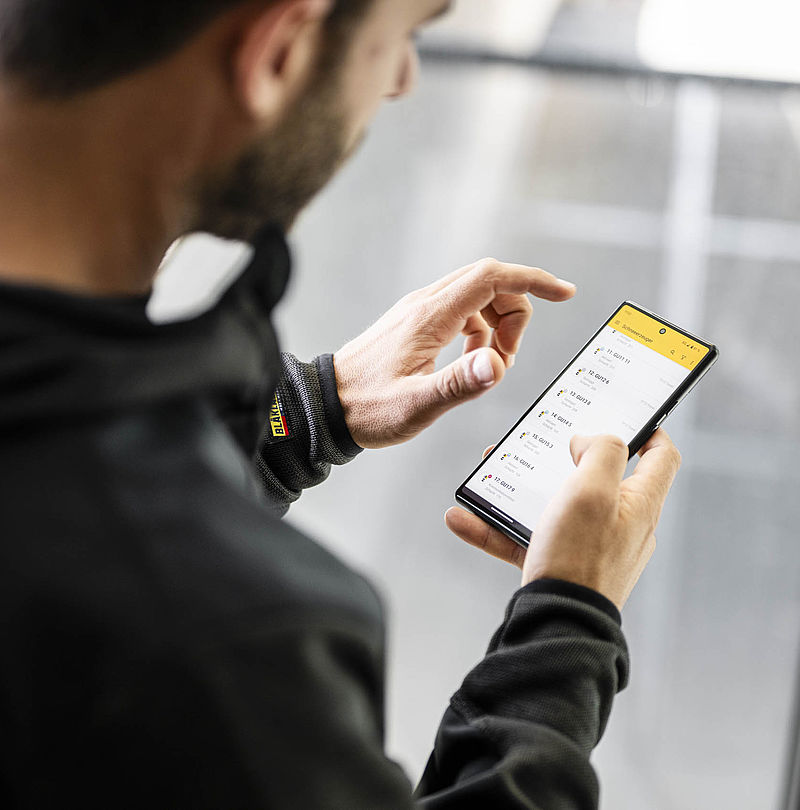 Mann bedient ATASSpro App auf Smartphone zur Steuerung von Schneeerzeugern