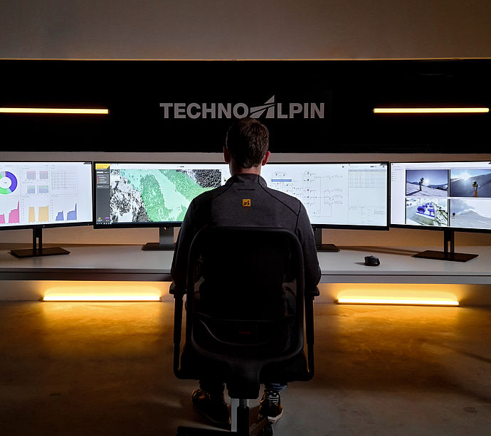TechnoAlpin Leitstand mit Mitarbeiter und Multi-Monitor-Setup zur Beschneiungssteuerung