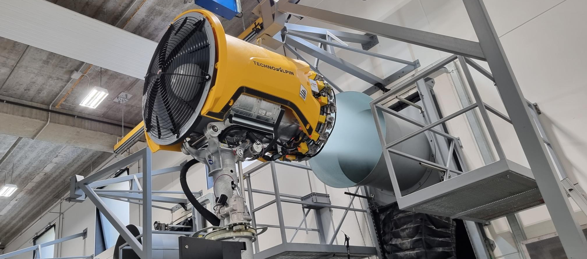 Gelbe TechnoAlpin Propeller-Schneekanone in Test- und Produktionshalle mit Stahlkonstruktion
