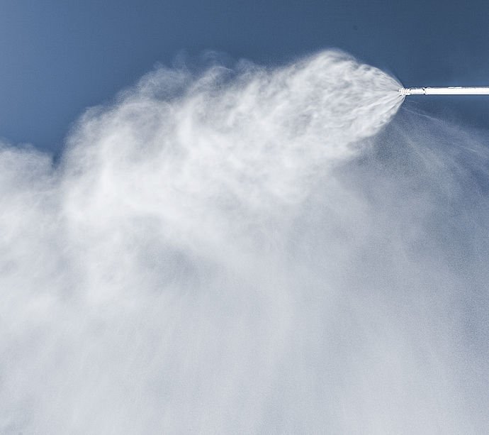 Schneestrahl einer TechnoAlpin Snowlance vor blauem Himmel beim Beschneien