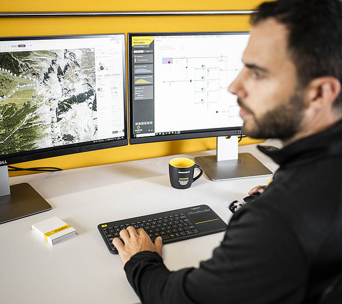TechnoAlpin Mitarbeiter am Arbeitsplatz mit Beschneiungssoftware auf zwei Monitoren